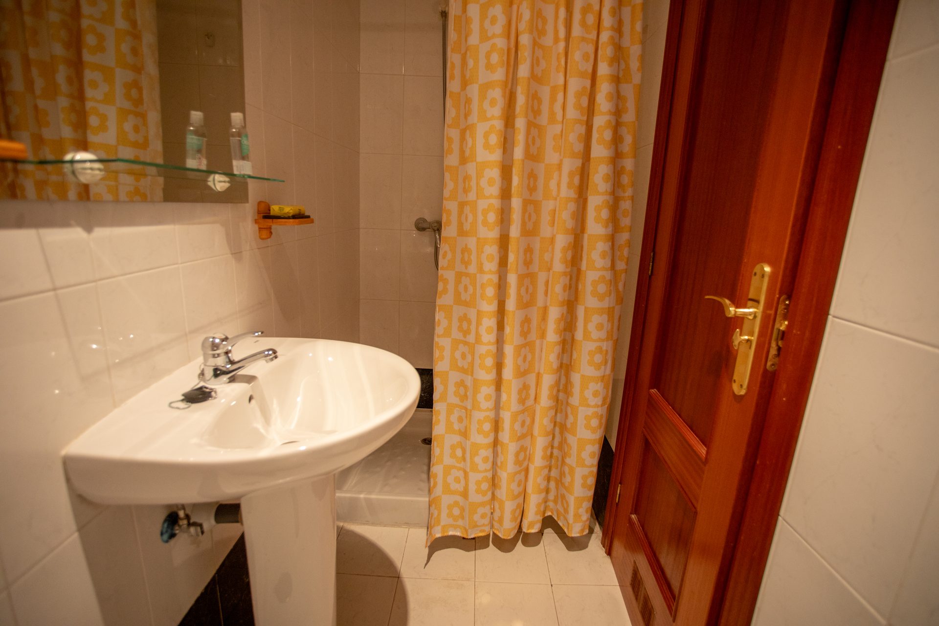 Baño con ducha y cortina amarilla de flores