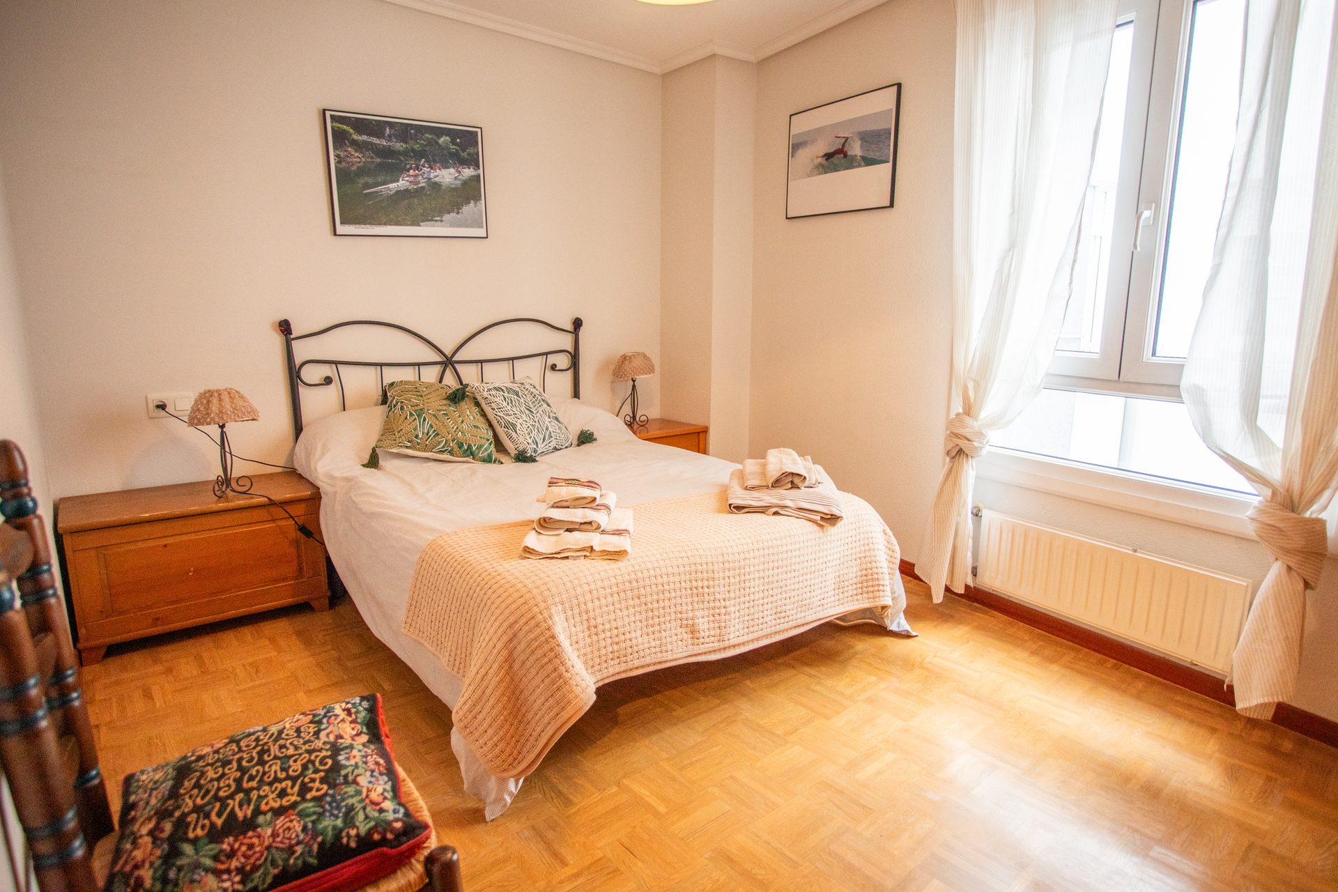 Dormitorio con cama de forja negra y cuadros de Asturias